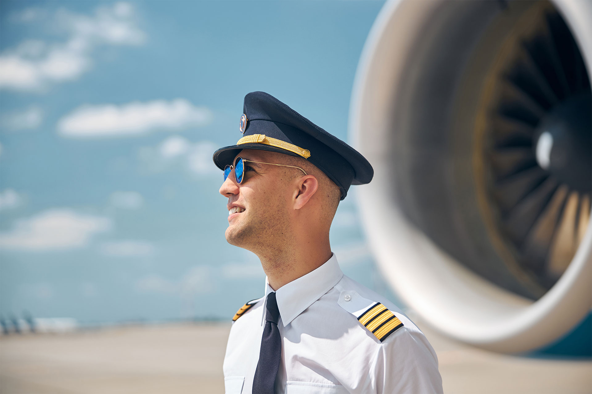 cheerful-pilot-in-sunglasses-standing-outdoors-in-BX8GZXE.jpg